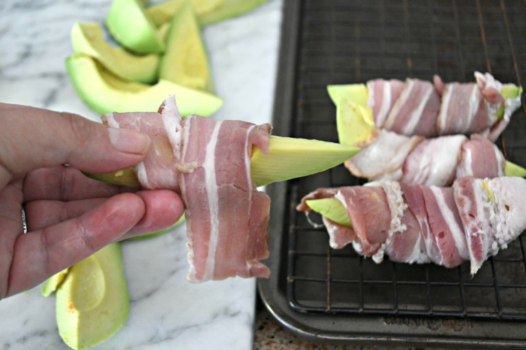 wrapping an avocado slice with bacon