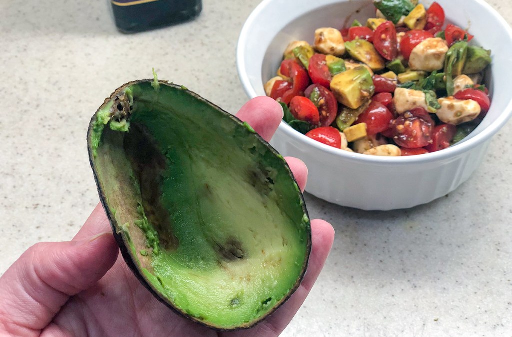 avocado shell with bowl of caprese salad