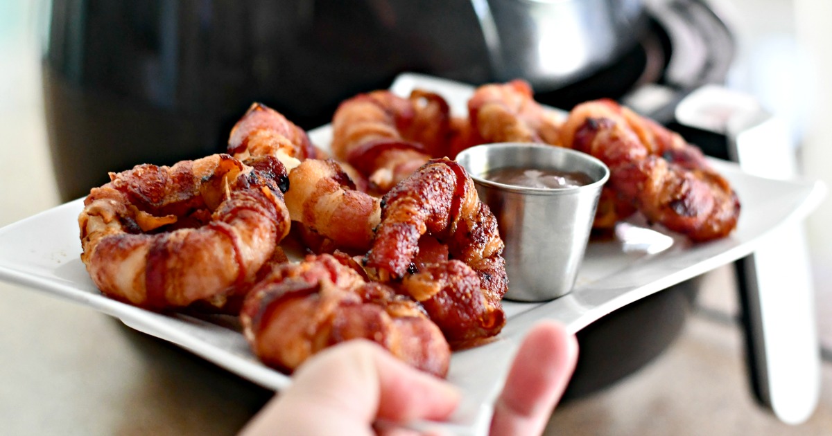 holding a plate of bacon wrapped air fryer onions rings