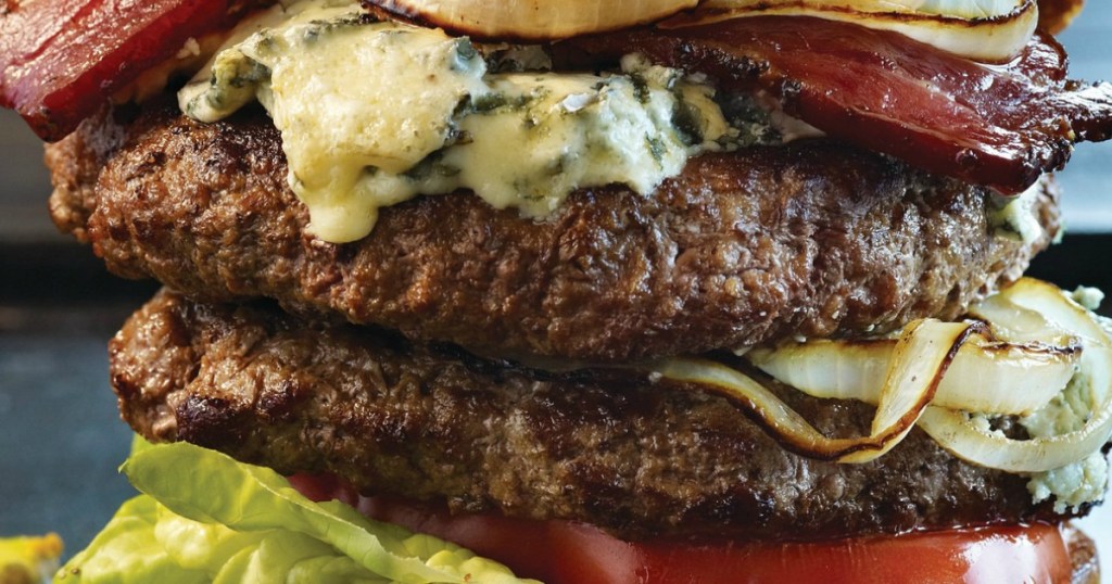 two large burger patties with onions, tomatoes, and bacon 