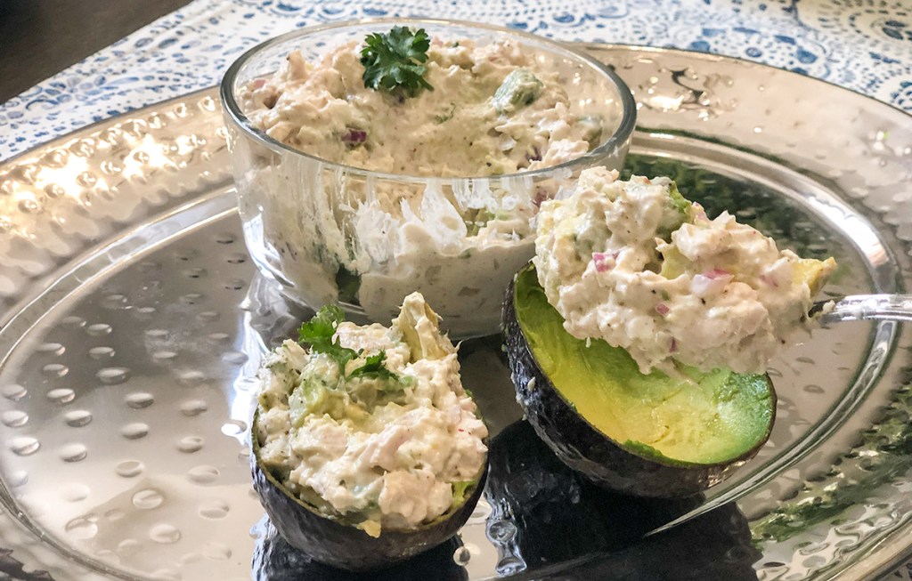 scooping chicken salad into avocado boats