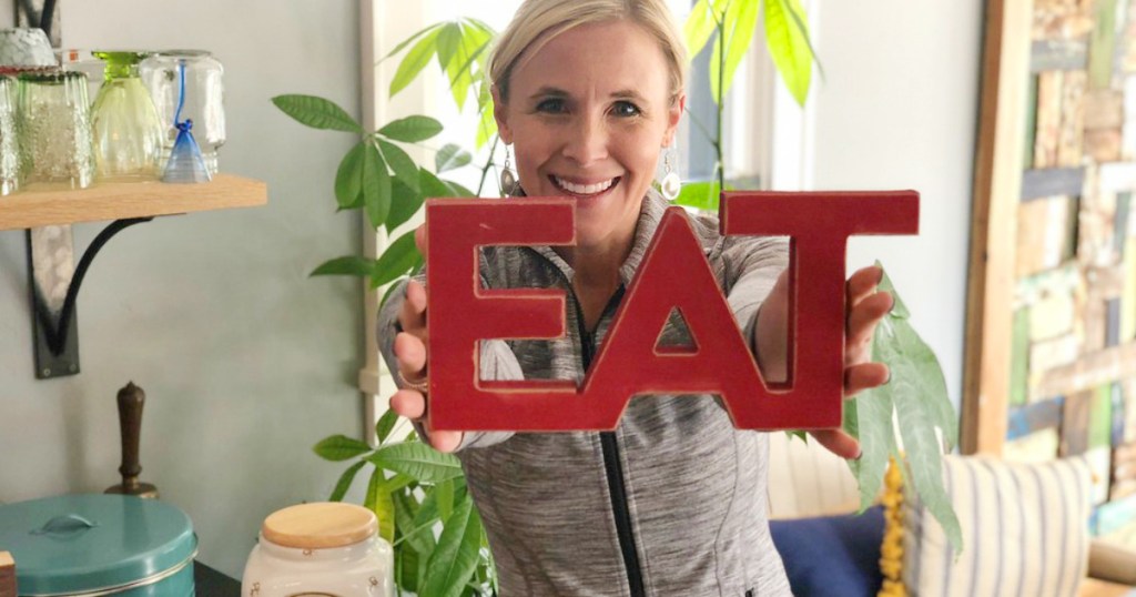 woman holding up sign that says "eat"