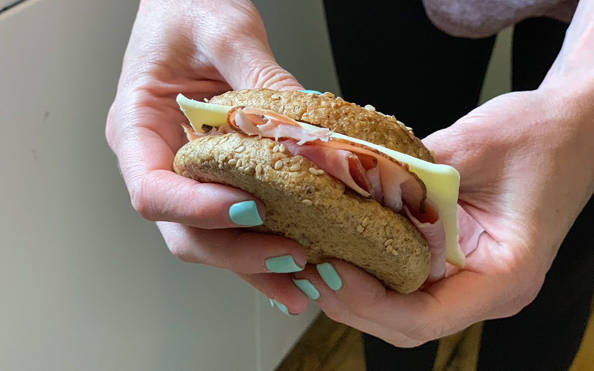 woman holding ham and cheese sandwich on omega bun