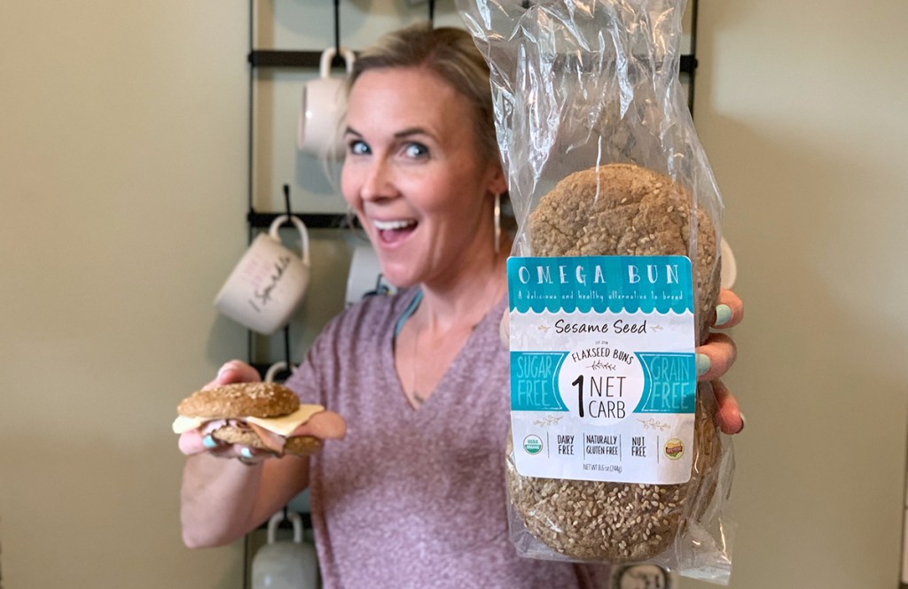 woman holding up sandwich and omega bun package