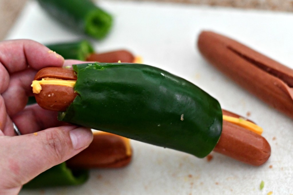 holding a stuffed cheese hot dog 