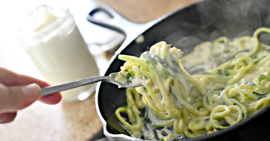 eating skillet alfredo zoodles with a fork 