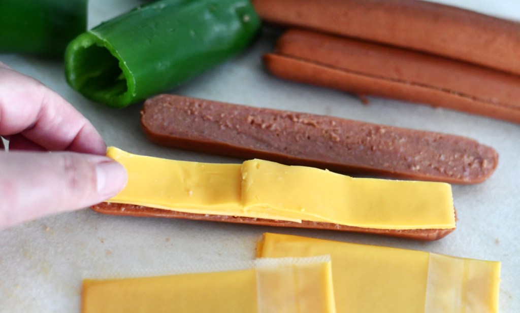 adding cheese to jalapeno hot dog