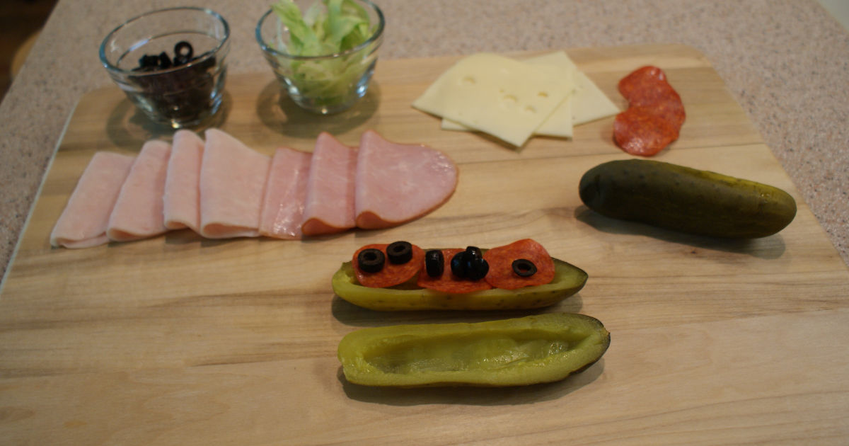 adding pepperoni, black olives, and other ingredients to a pickle sandwich
