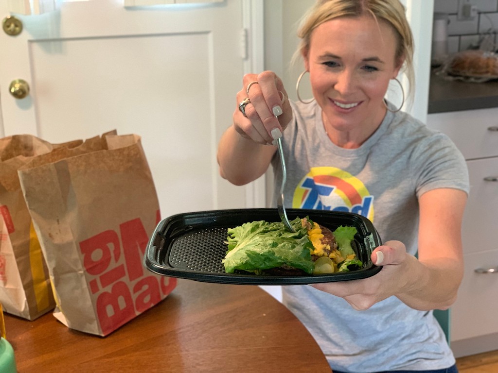 Woman holding on platter bunless Mcdonald's quarter pounder with cheese