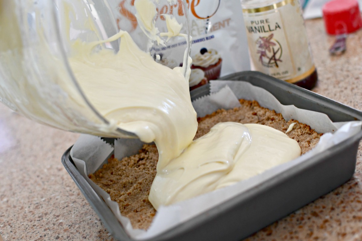 pouring cheesecake filling into pan