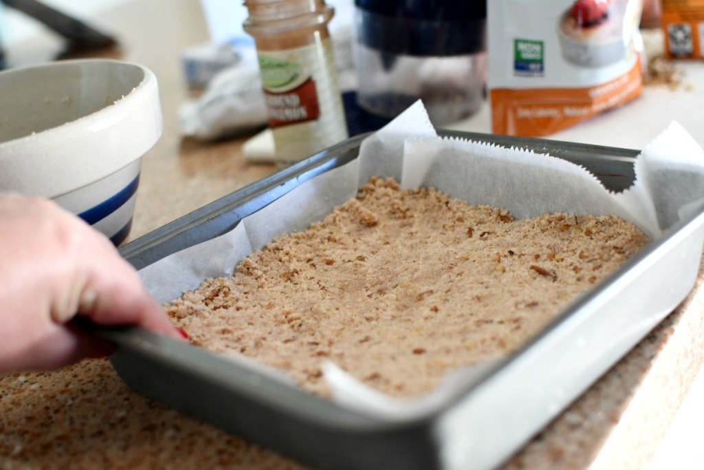 pressing a crust into pan for keto pecan bars