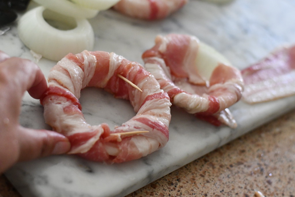 securing bacon with toothpicks to onion 