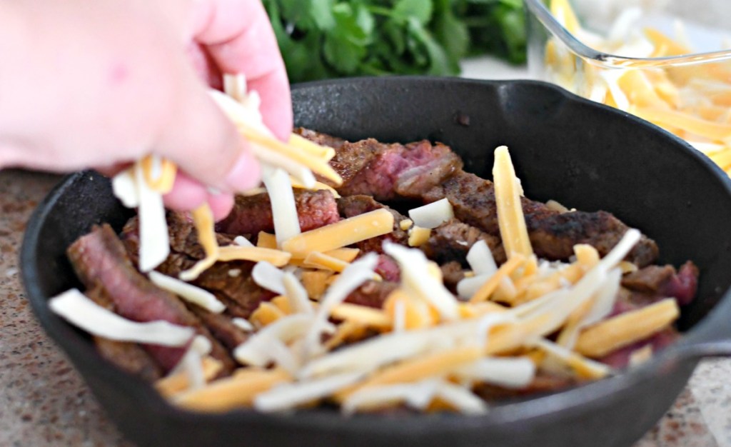 topping sliced steak with cheese for steak nachos