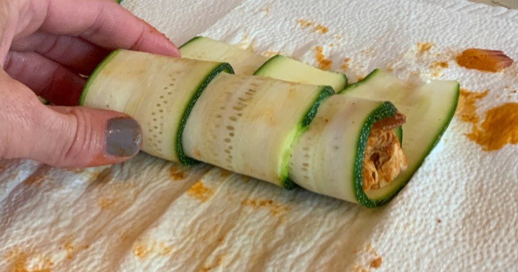 rolling up keto zucchini enchiladas 