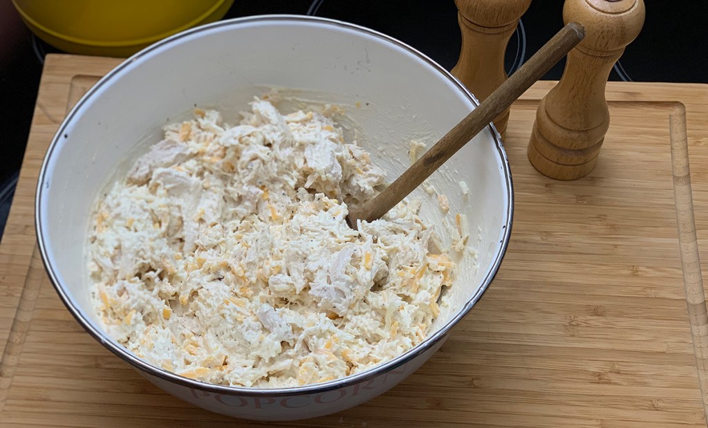 mixing shredded chicken and cheese in bowl