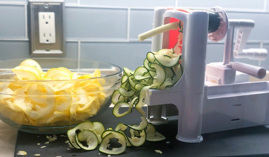 spiralizing green zucchini through spiralizer