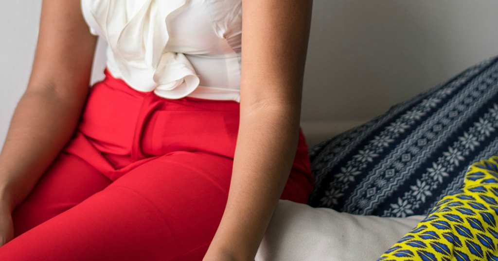 woman sitting on bed wearing red pants 