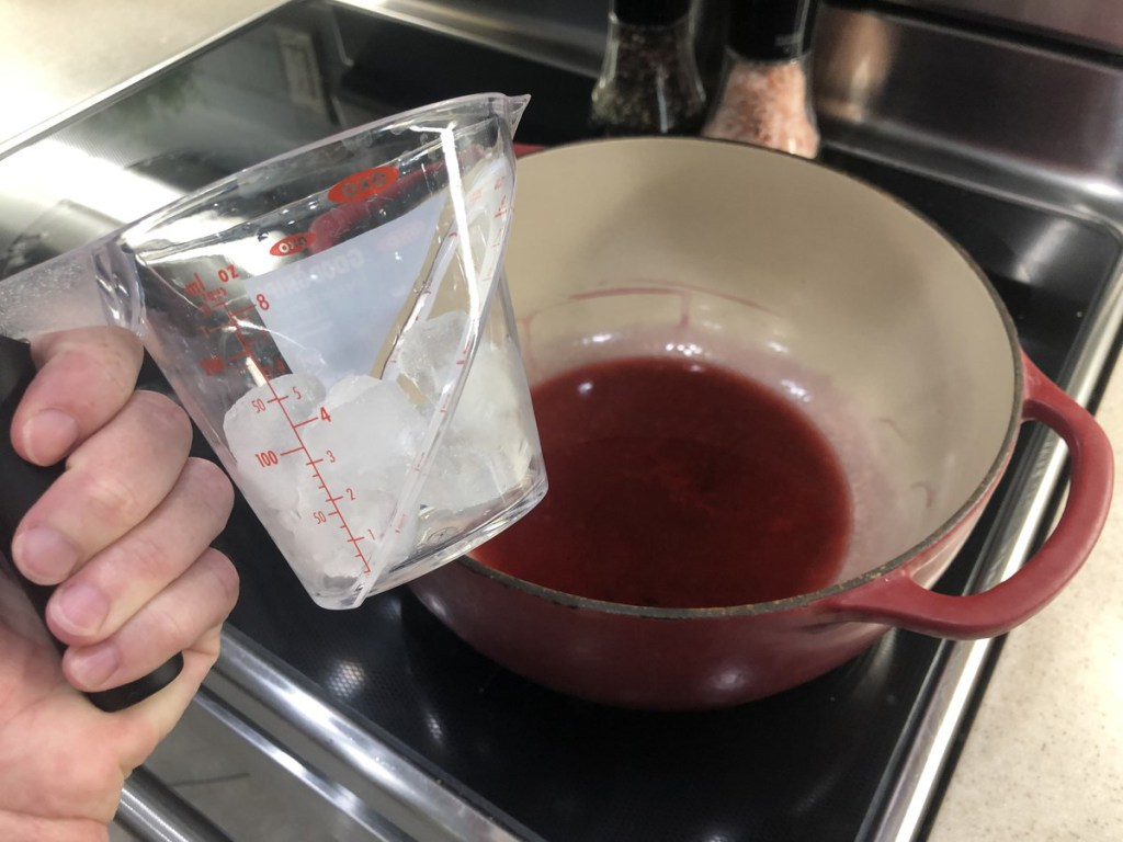 ice in measuring cup above steeped tea on stove