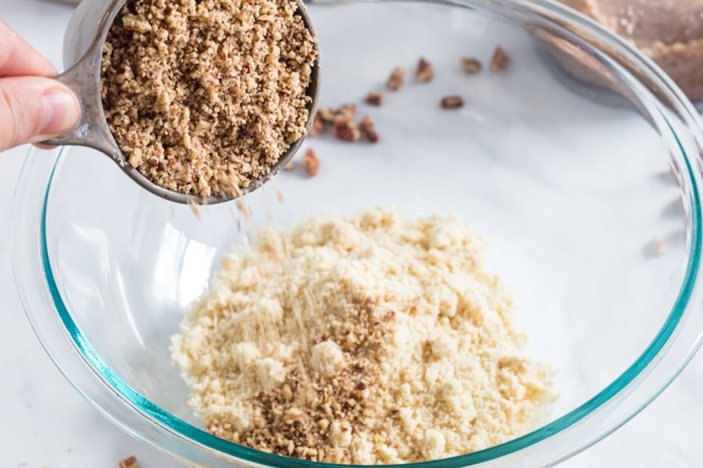 pouring crushed pecans into almond flour