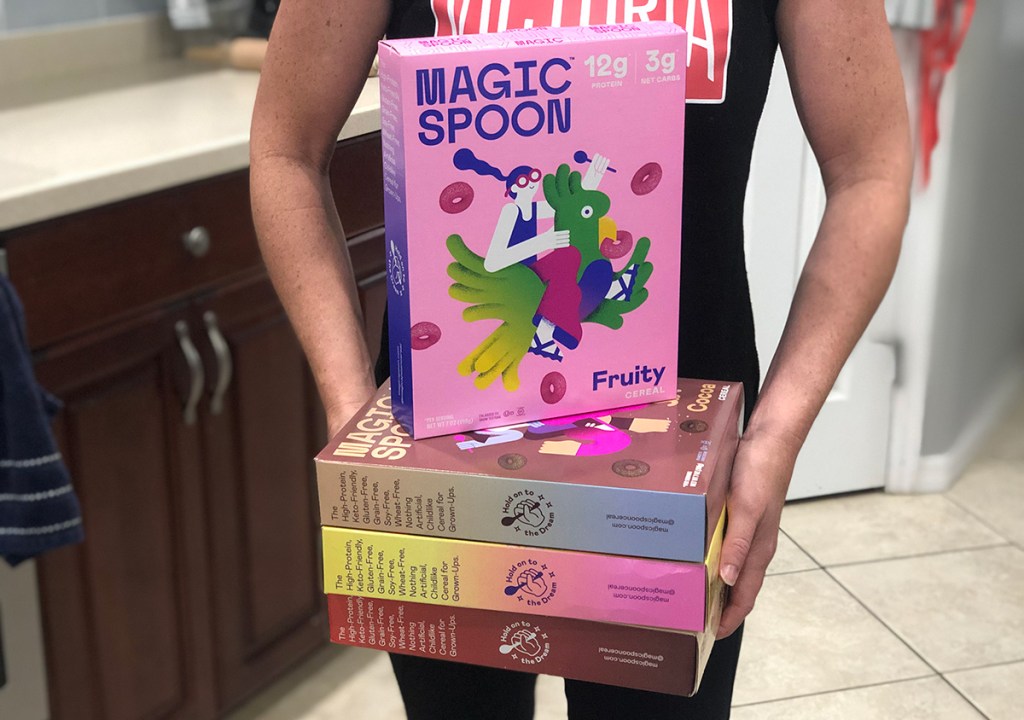 woman holding magic spoon cereal boxes