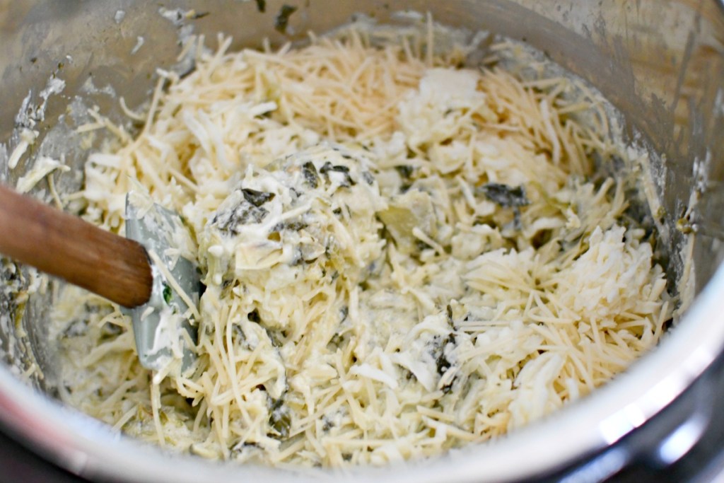 mixing in parmesan cheese to keto artichoke dip