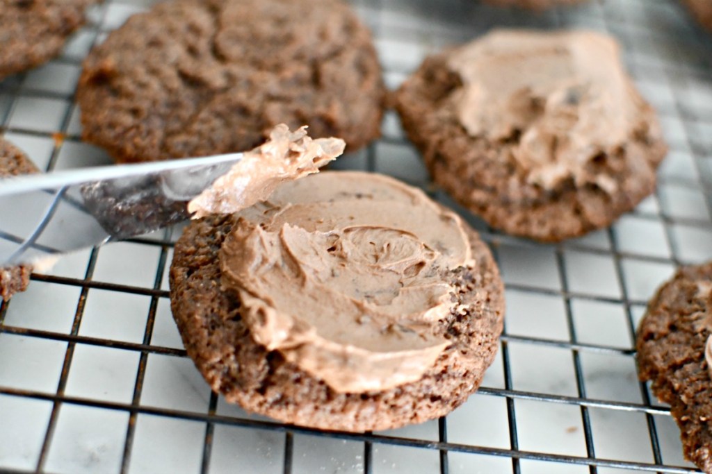 spreading chocolate icing on keto cookies