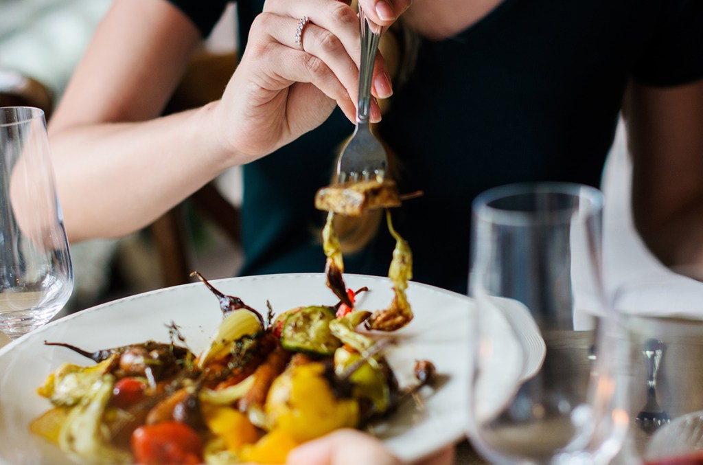 woman with fork of roasted vegetables