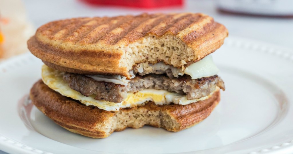 Bite taken out of Keto McGriddle Breakfast Sandwich on plate