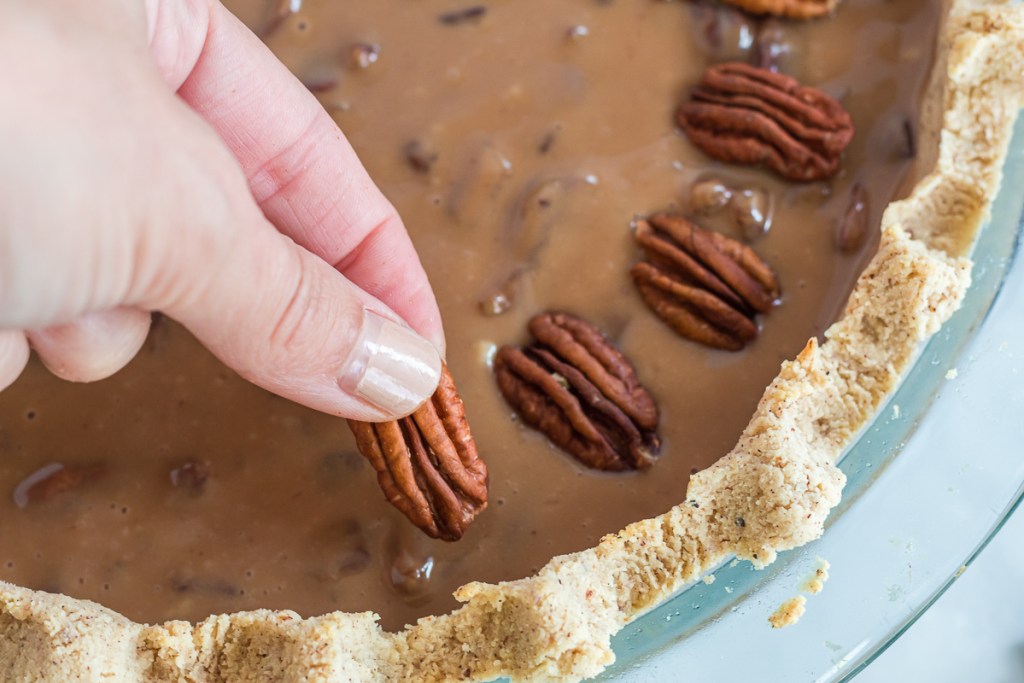 putting pecan halves on unbaked keto pecan pie