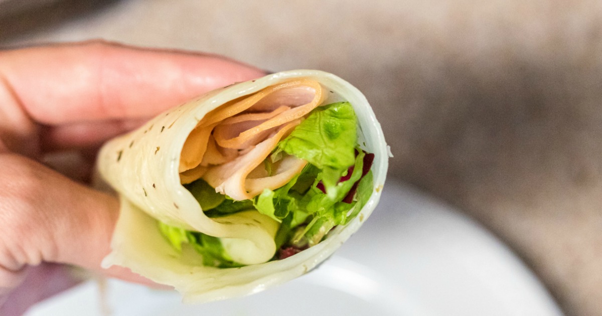 Person holding Keto Cheese Wrap filled with lettuce and turkey