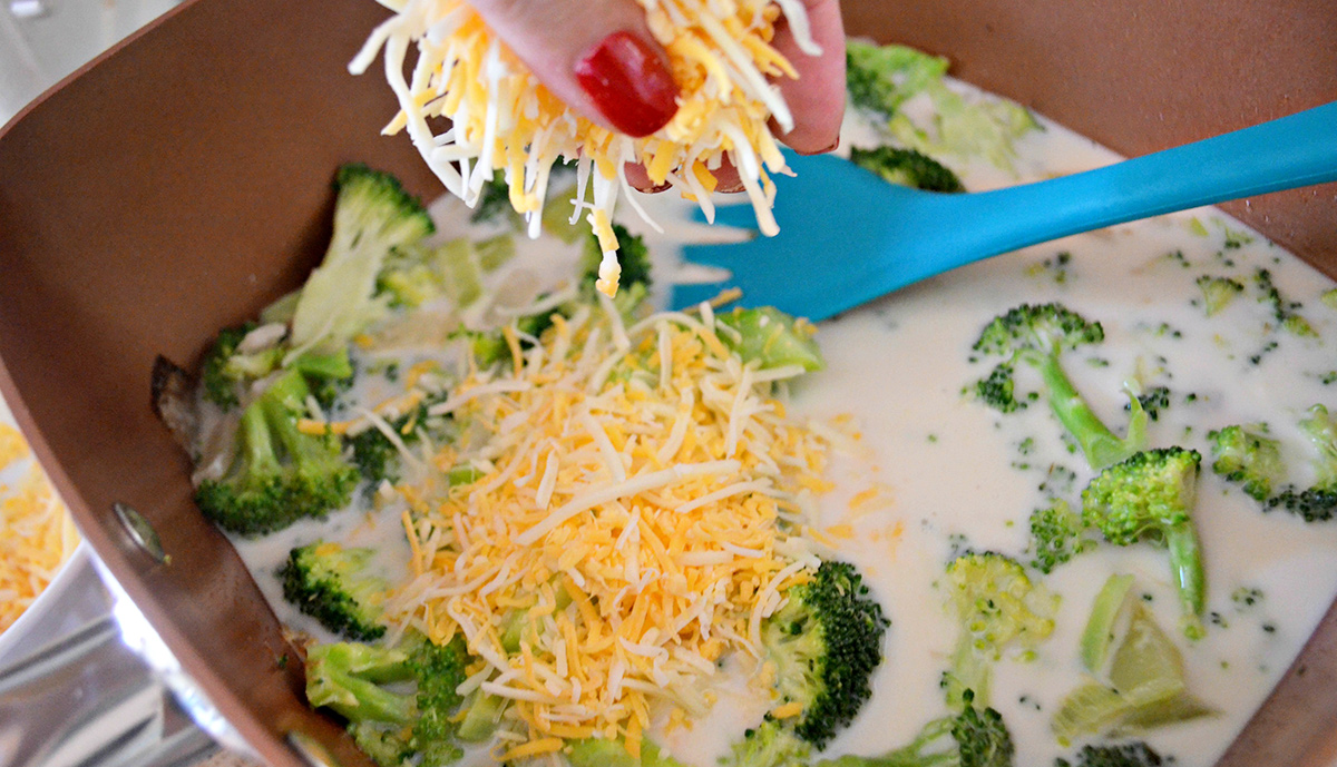 sprinkling cheese into broccoli cheddar soup