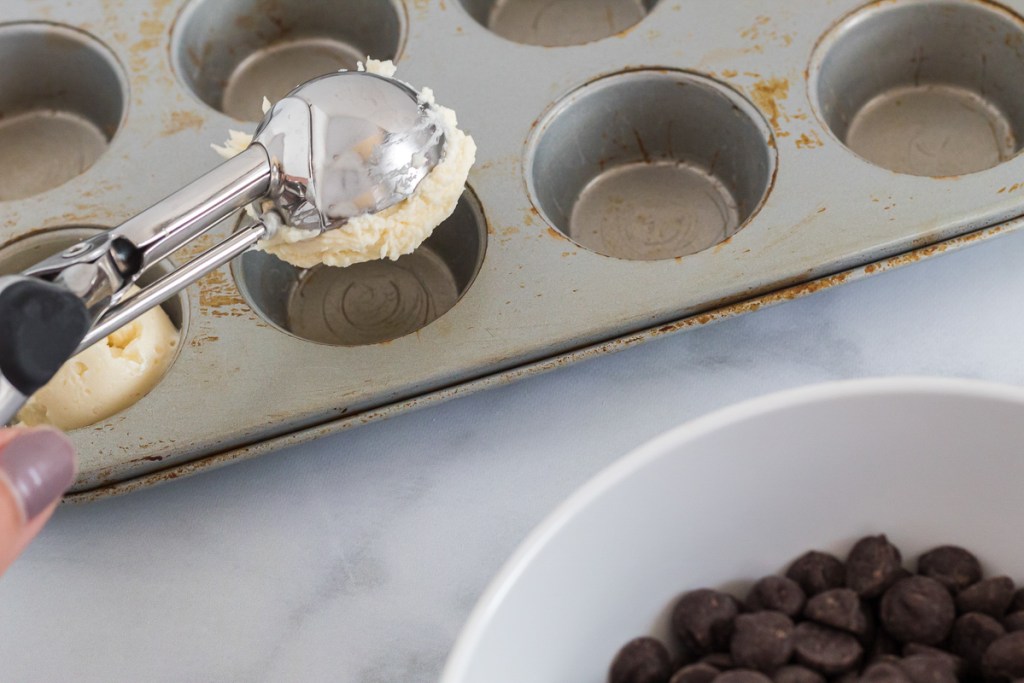 scooper with cheesecake filling into muffin tin