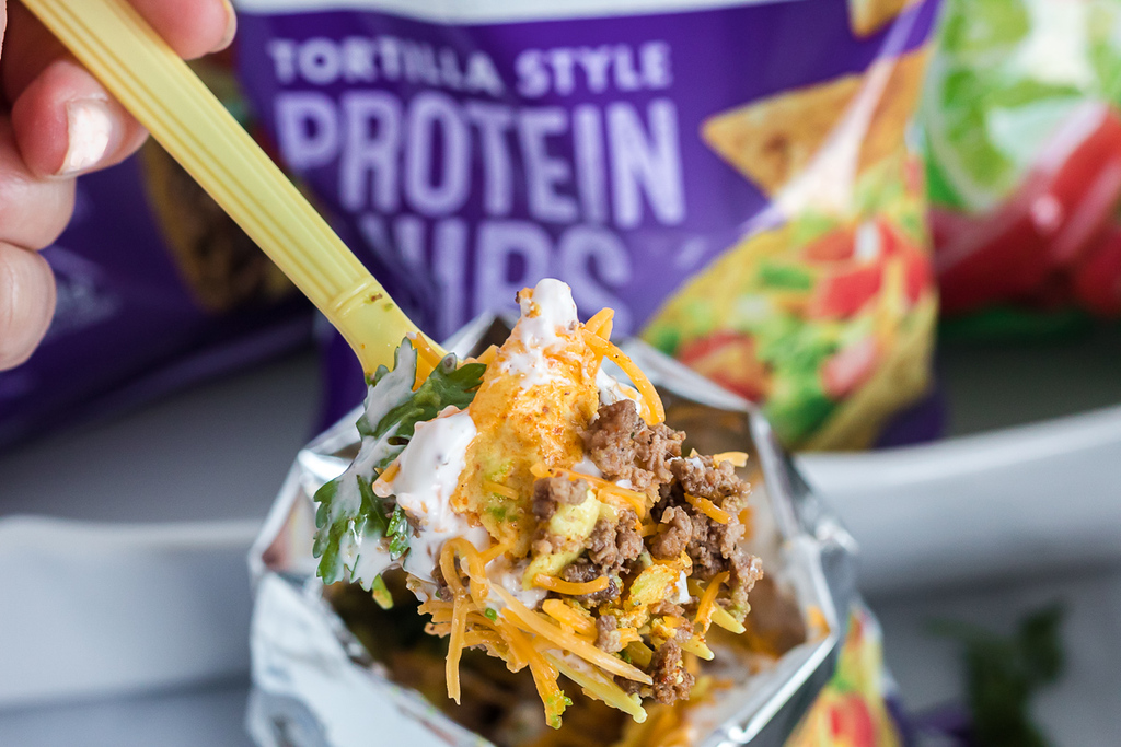taking a fork out of Quest chips bag with taco toppings 