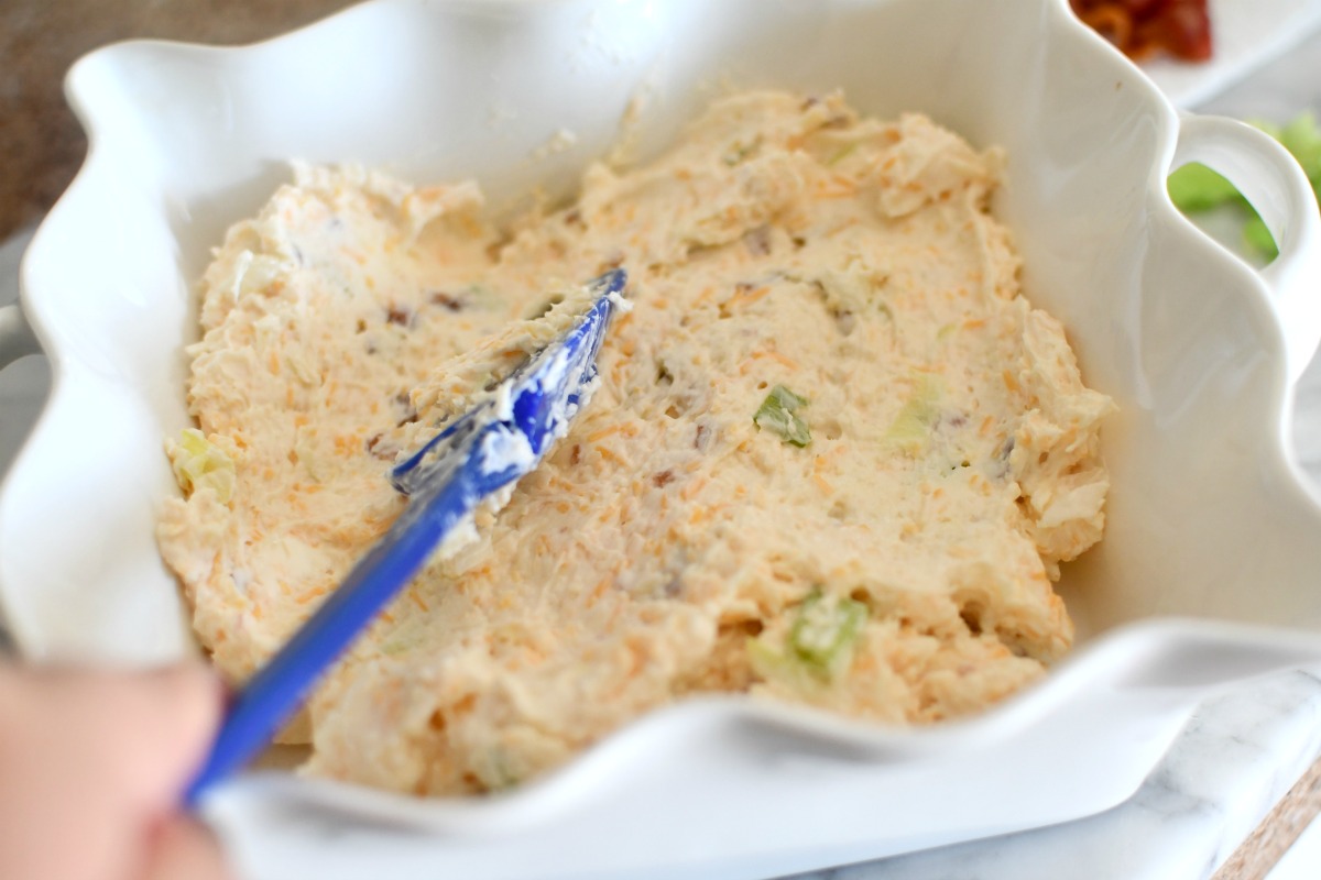 spreading warm bacon dip into a casserole dish