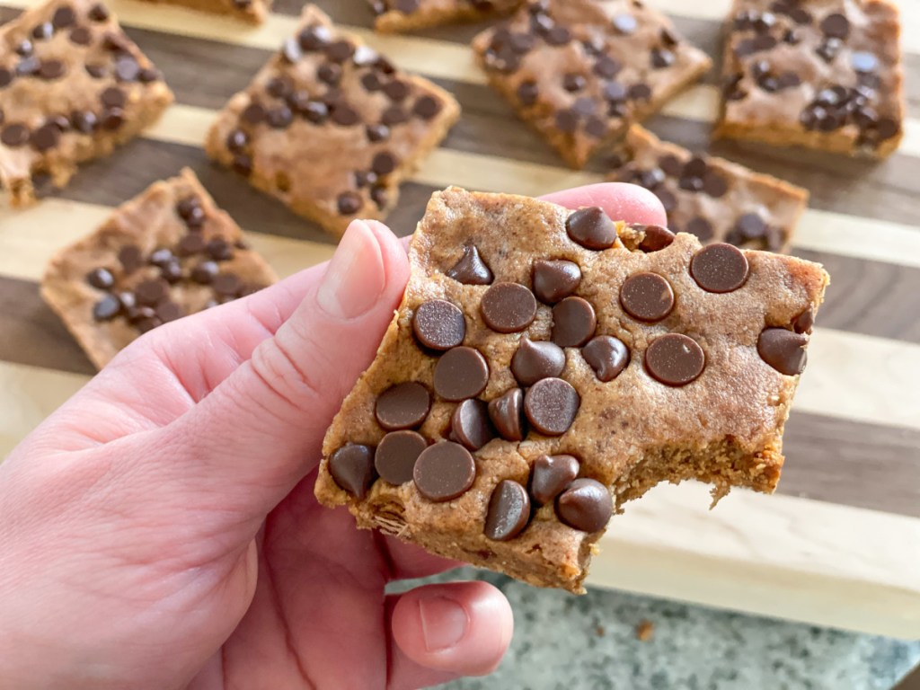 holding a cookie dough protein bar with a bite out of it 