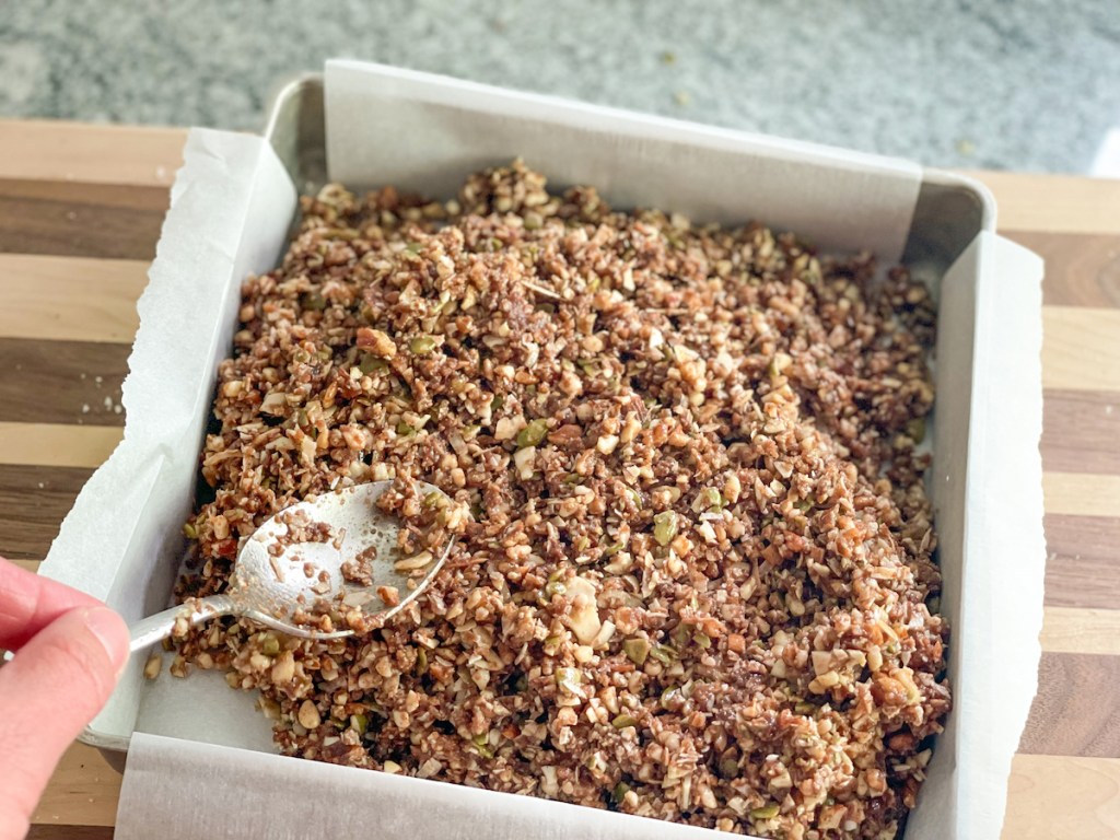 pressing keto nut mixture into a pan for keto granola bars 
