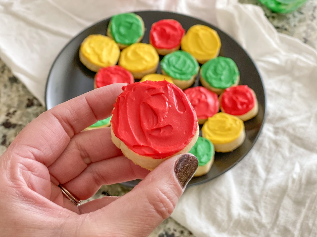 holding frosted keto sugar cookie round
