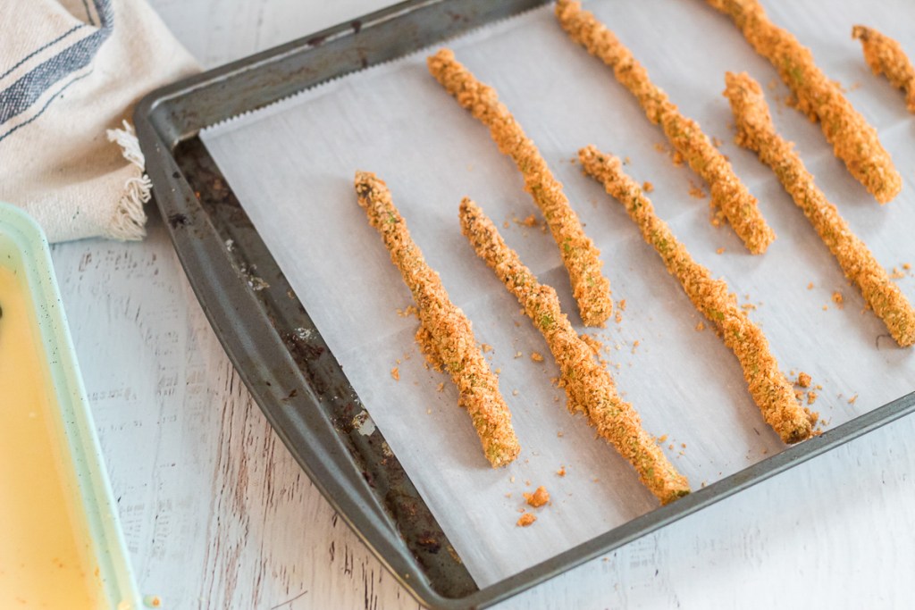 breaded asparagus on a baking sheet 