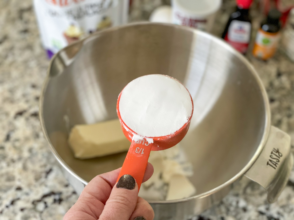 adding keto sweetener to mixing bowl for soft keto sugar cookies