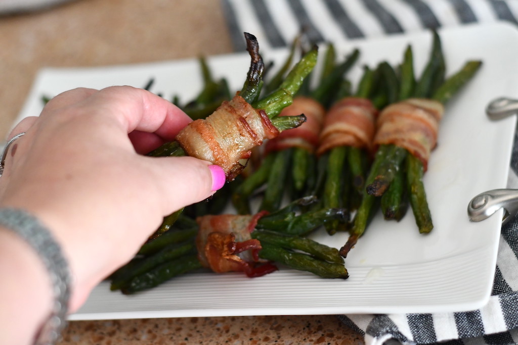 holding bacon-wrapped green bean bundle 