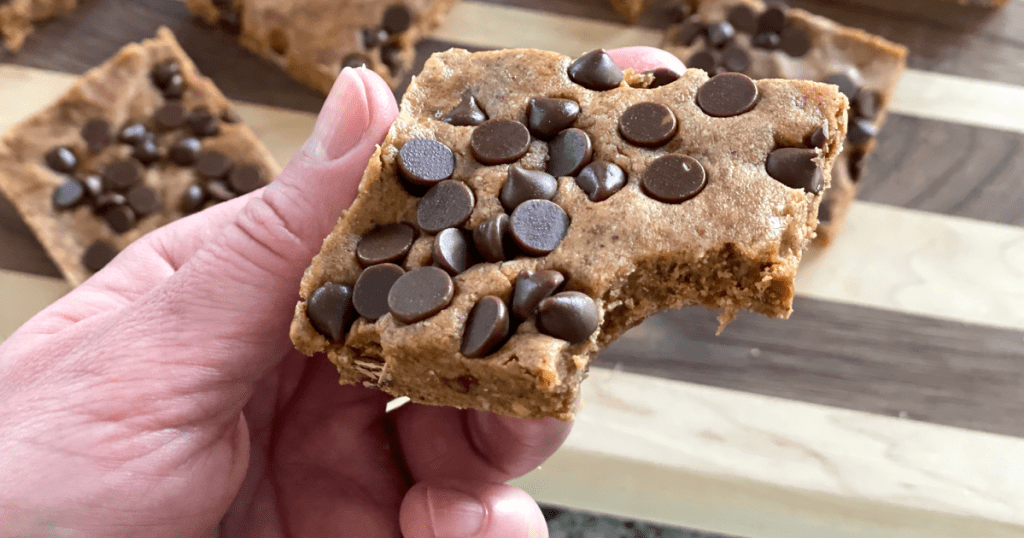 taking bite of keto chocolate chip protein bars 