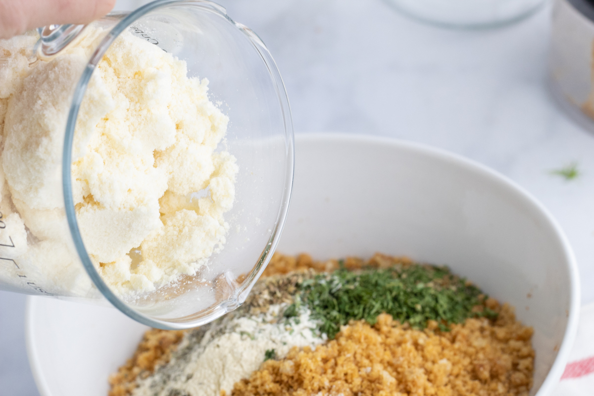 pouring parmesan cheese into bread crumbs seasoning blend 