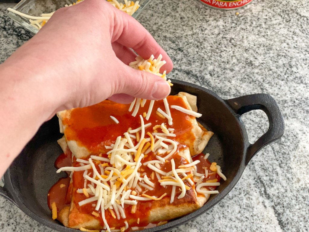 adding shredded cheese to the top of burritos
