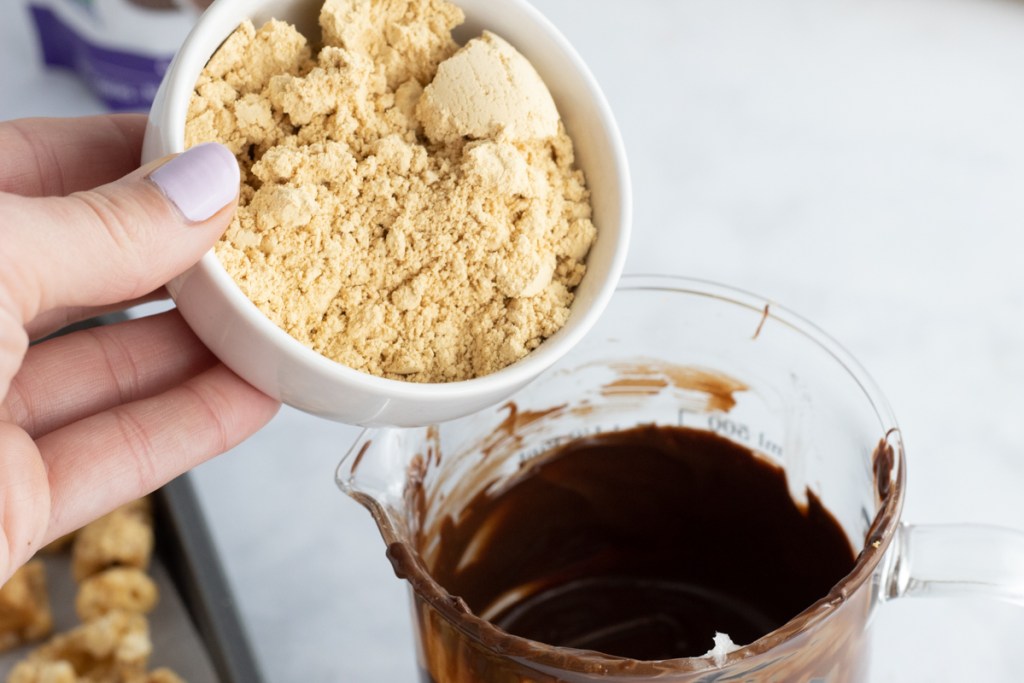 pouring PB Fit powder into melted chocolate