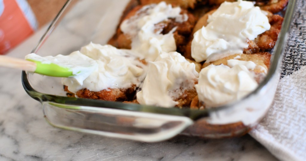 adding frosting to cinnamon rolls