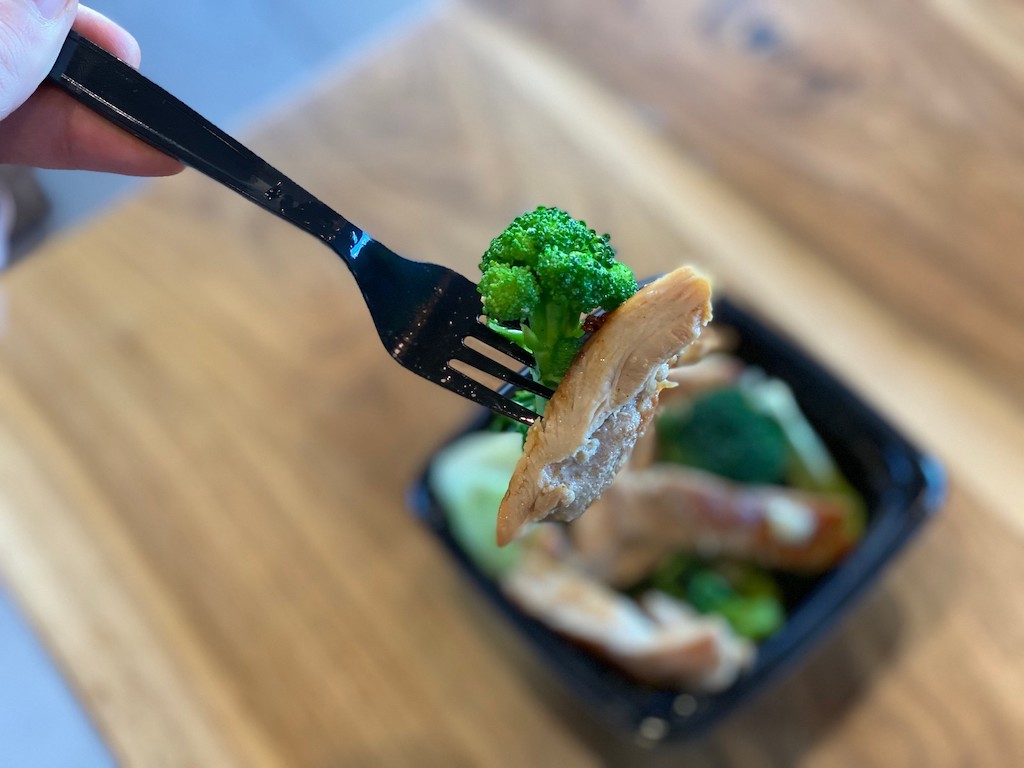 Håller gaffel med broccoli och grillad kyckling från Panda Express