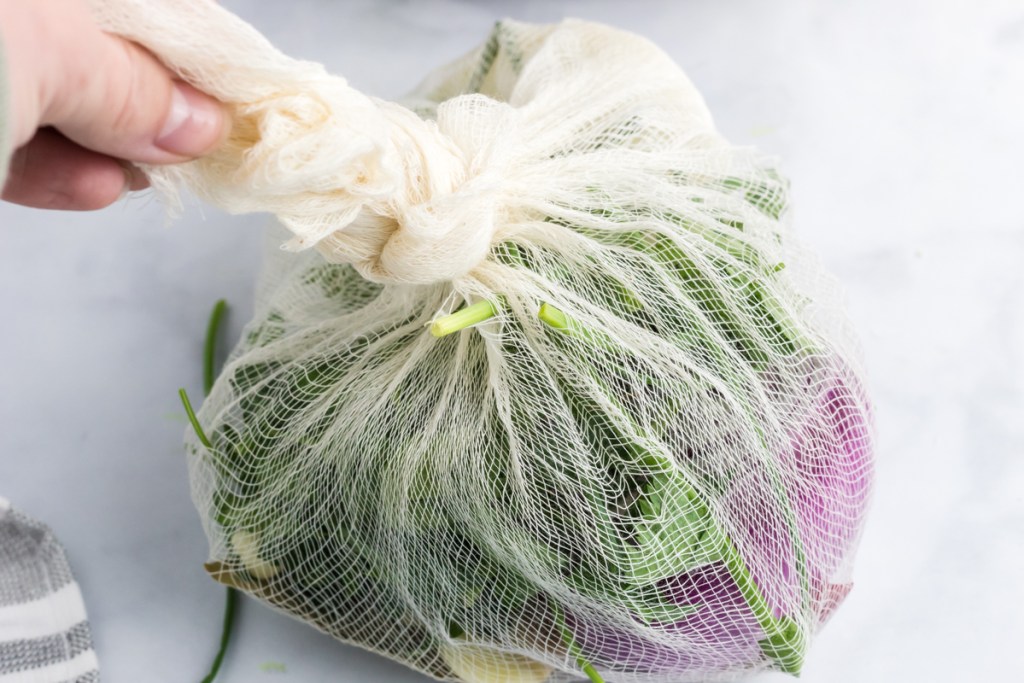 veggies and herbs are in a tied cheesecloth