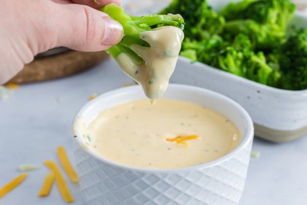 dipping broccoli into cheese sauce