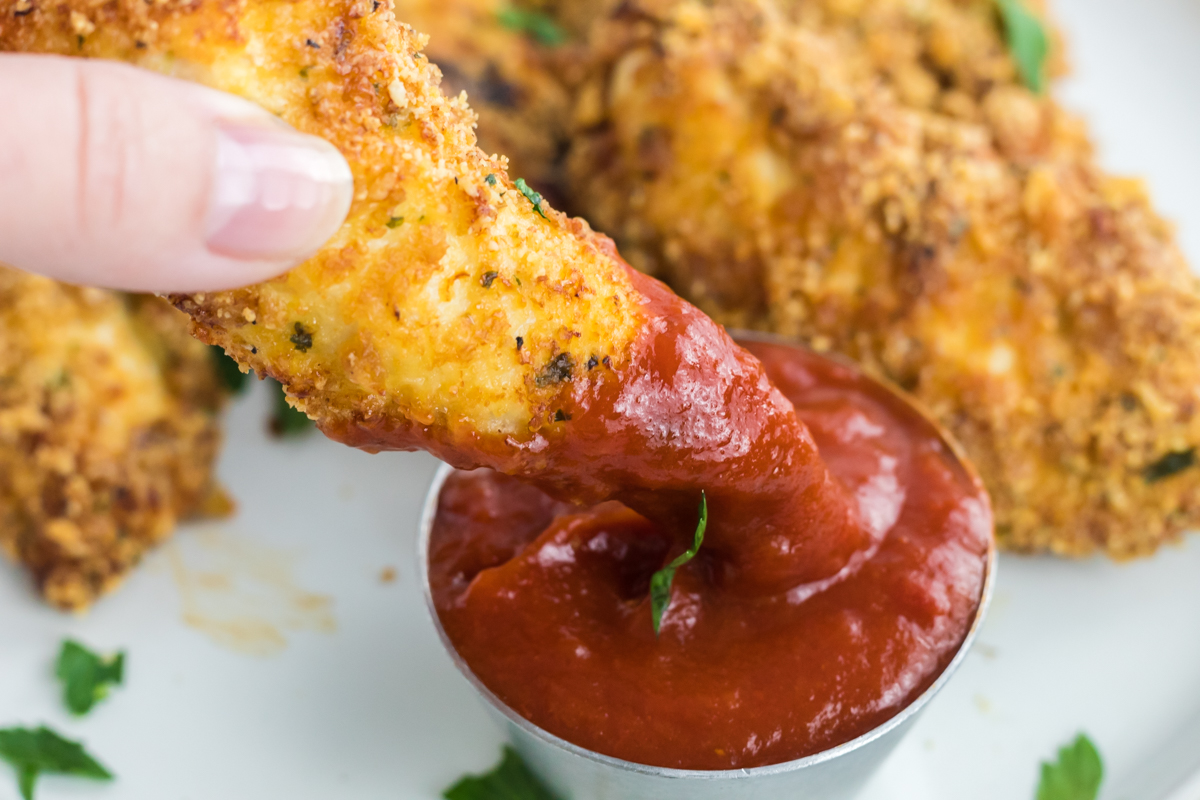 dipping chicken tender into homemade keto ketchup