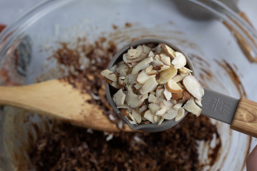 almond slices going into bowl of keto no bake cookies